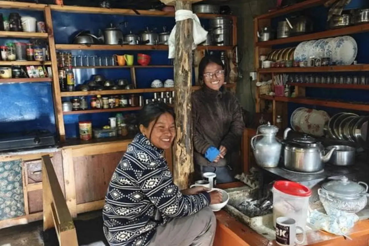 Friendly local women smiling inside a traditional kitchen during the Annapurna Base Camp Trek.