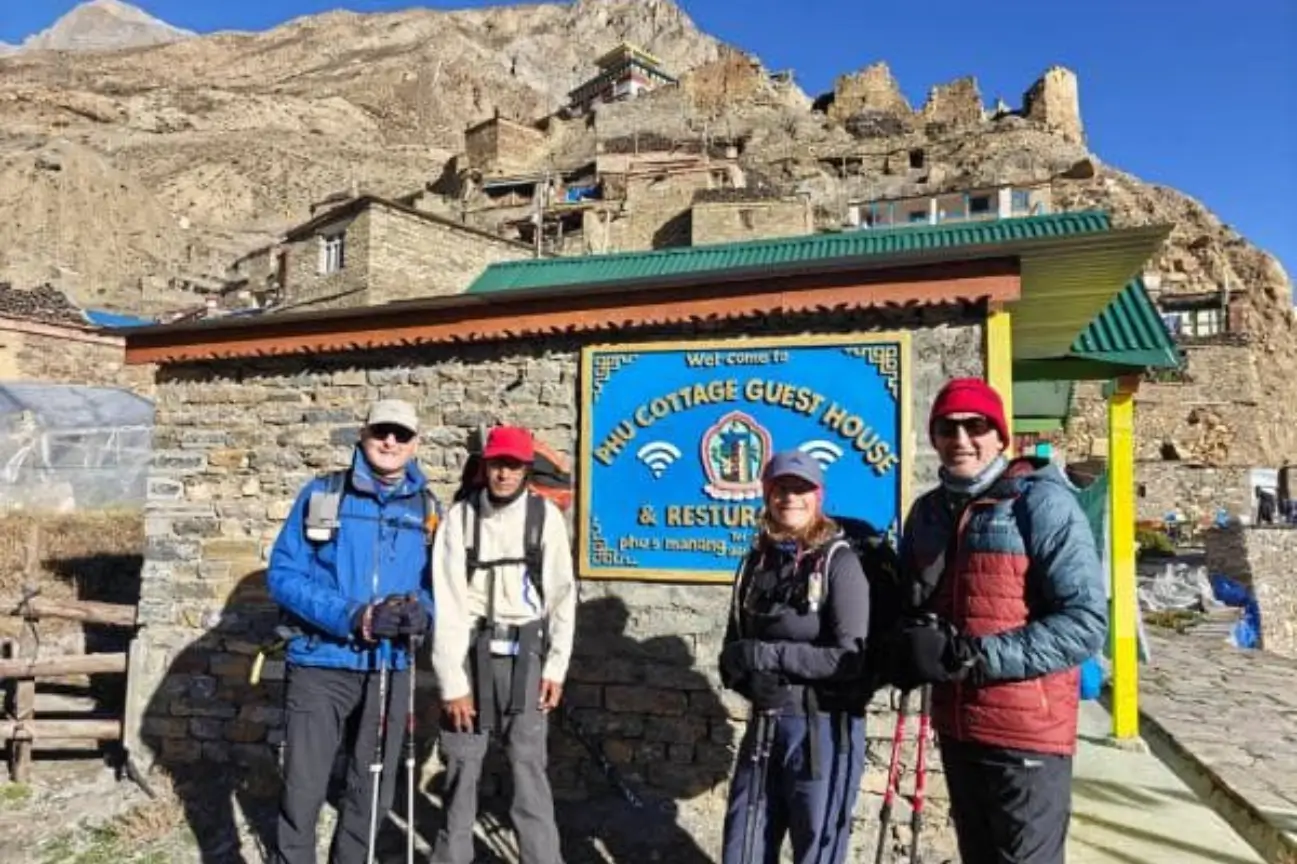 A group of hikers standing in front of the Phu Cottage Guest House and Restaurant in a historic mountain settlement along remote Camping Routes.