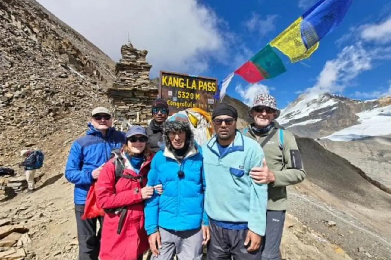 A happy group of travelers and a local guide standing together outdoors with red scarves under a bright sky for Family Tours.